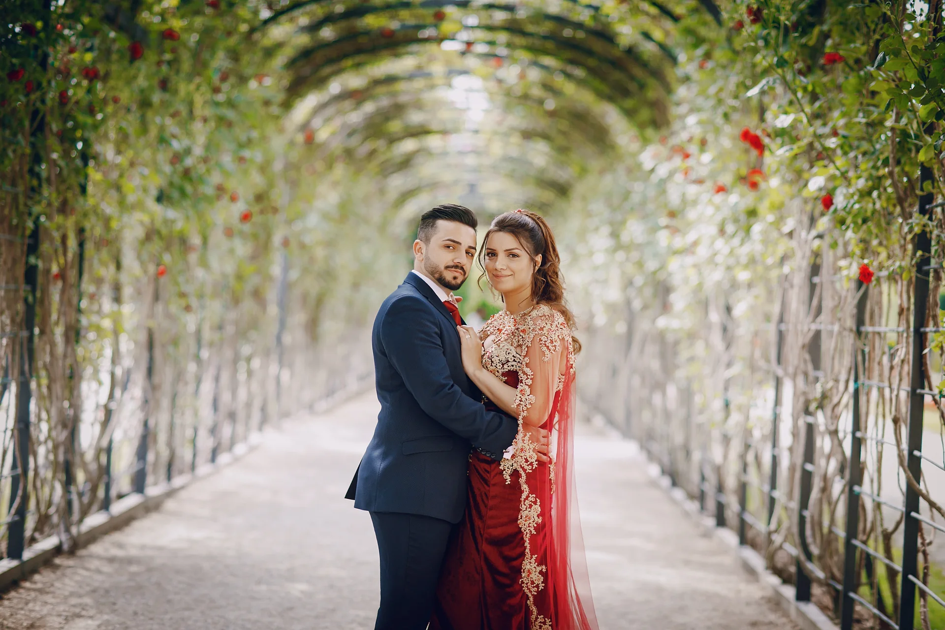 Couple standing together beneath a rose arch